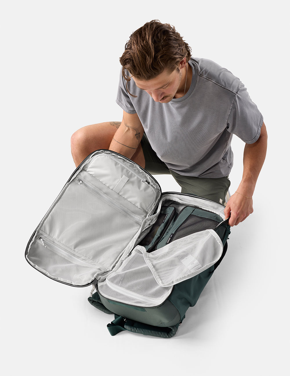 Person opening a gray backpack on a white background