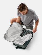 Person opening a gray backpack on a white background