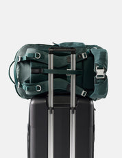 Green backpack on top of a black suitcase with a white background