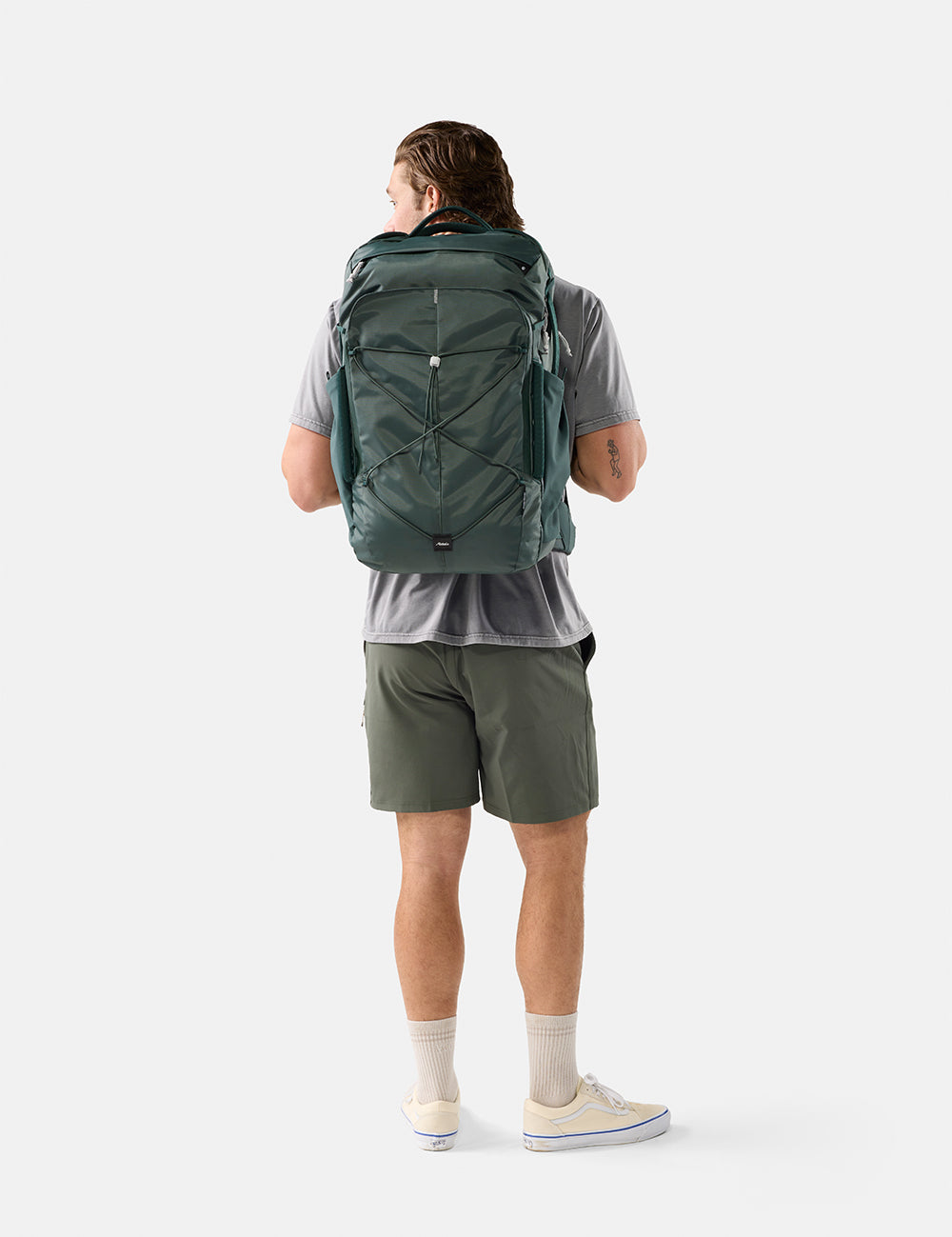Person wearing a green backpack on a white background