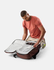 Man unpacking a large garnet backpack on a white background