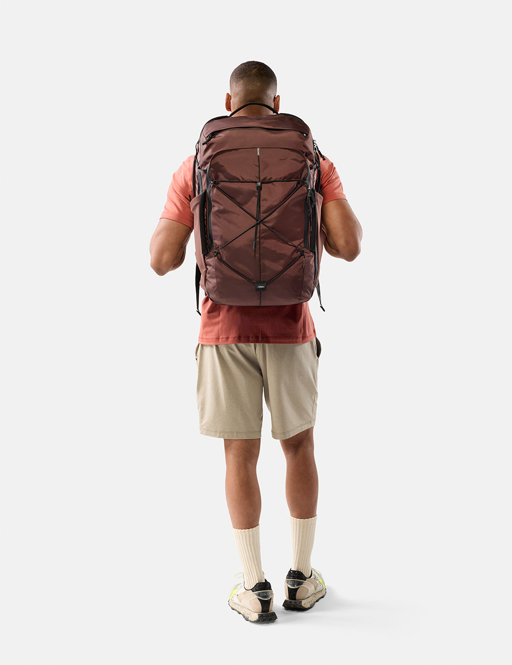 Person wearing a large garnet backpack on a white background