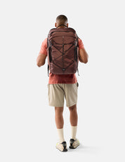 Person wearing a large garnet backpack on a white background