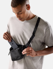 Man wearing a black waist bag with iphone on a light gray background