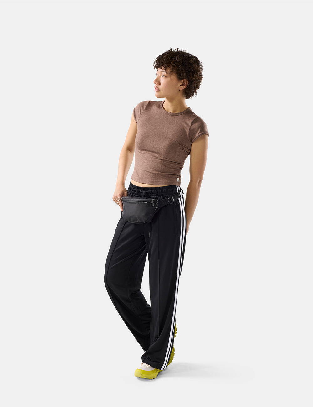 Person wearing a brown top and black pants with white stripes on a white background