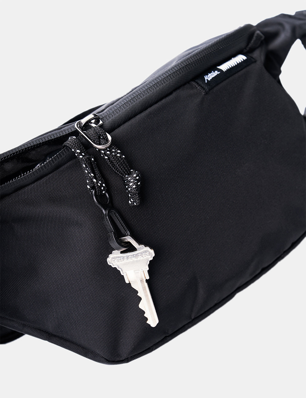 silver key tethered to sling bag