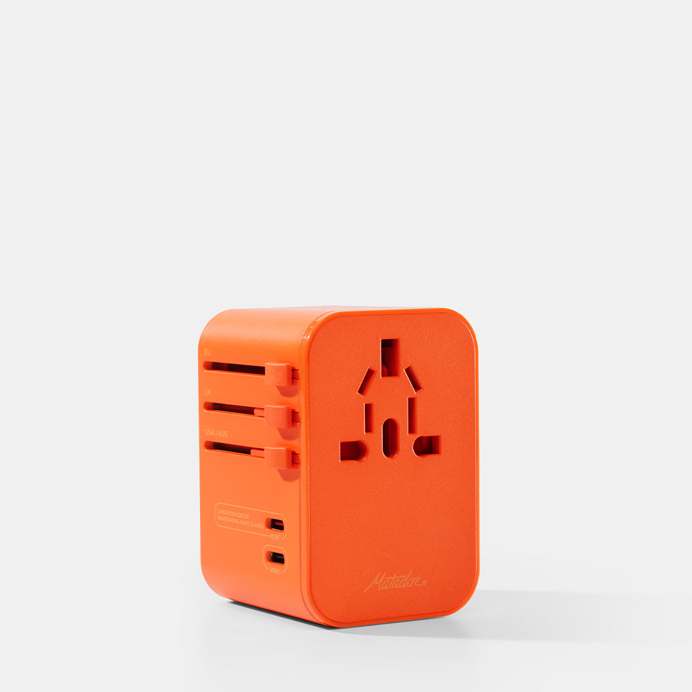 Orange travel adapter on a white background