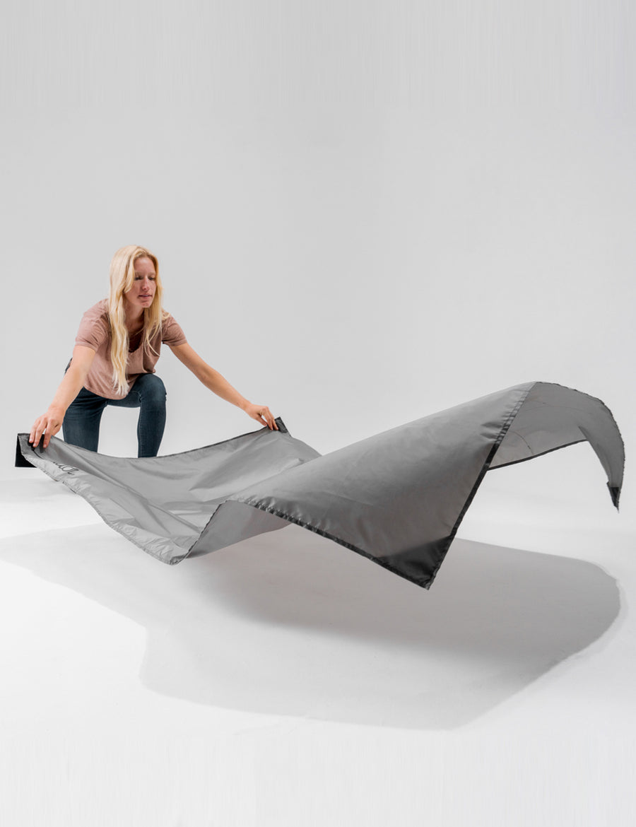woman laying out pocket blanket on white studio background