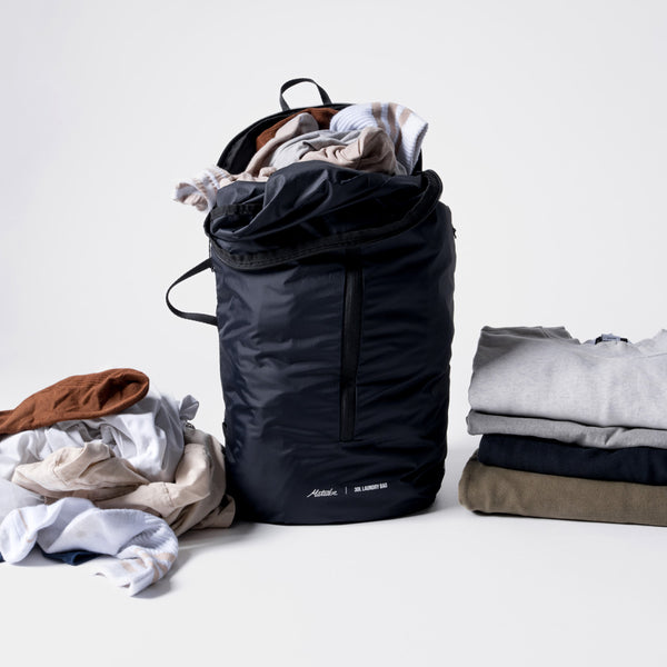 Full laundry bag on white background with dirty laundry to the left and folded laundry to the right