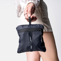 woman on white studio background, holding packed up laundry bag by the hang loo
