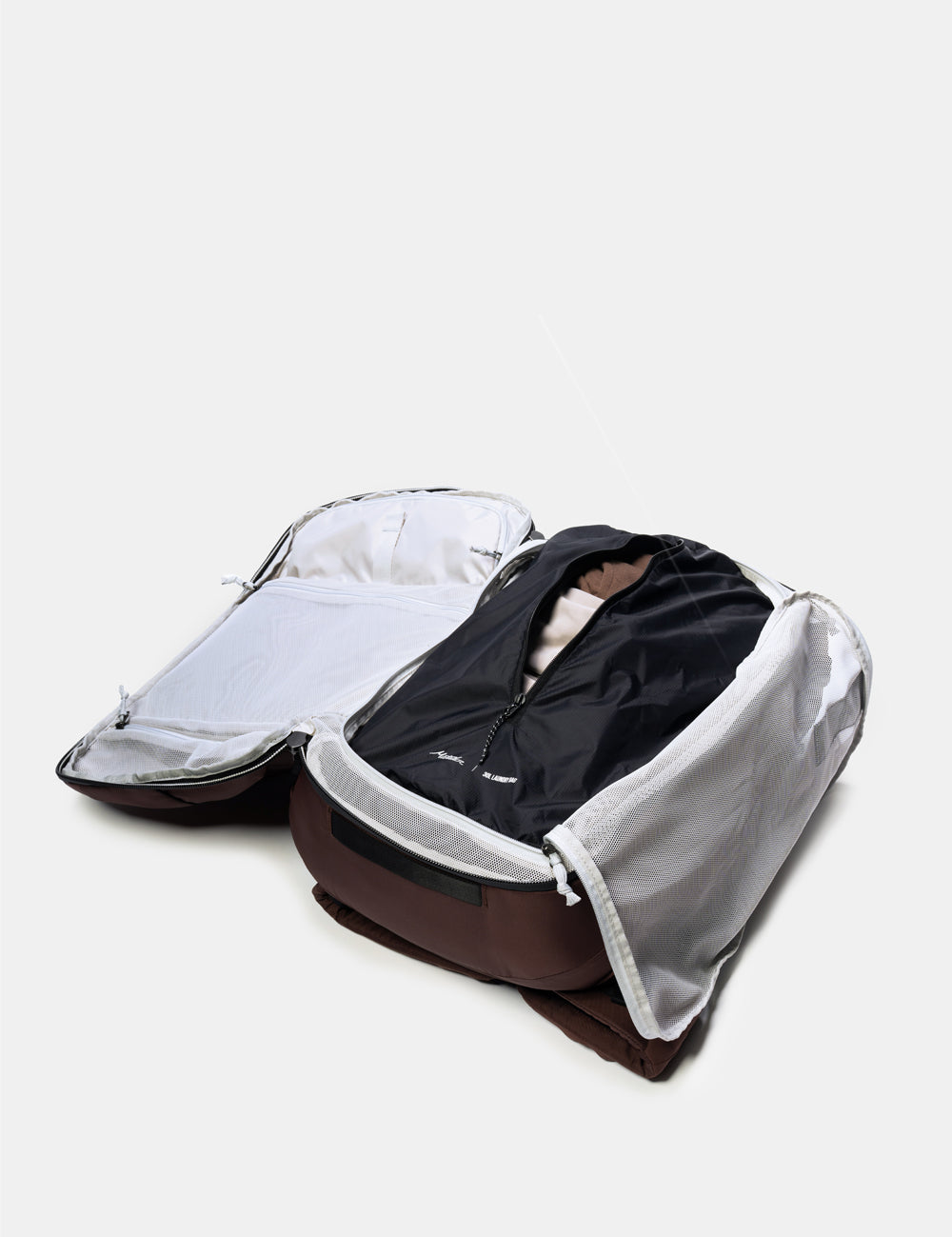 Open backpack with dirty clothes on a light gray background