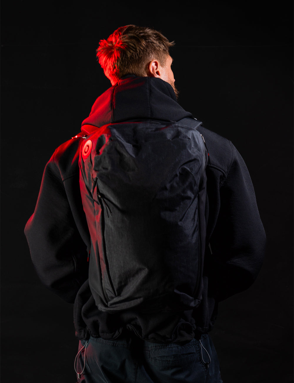 man wearing black backpack in dark setting
