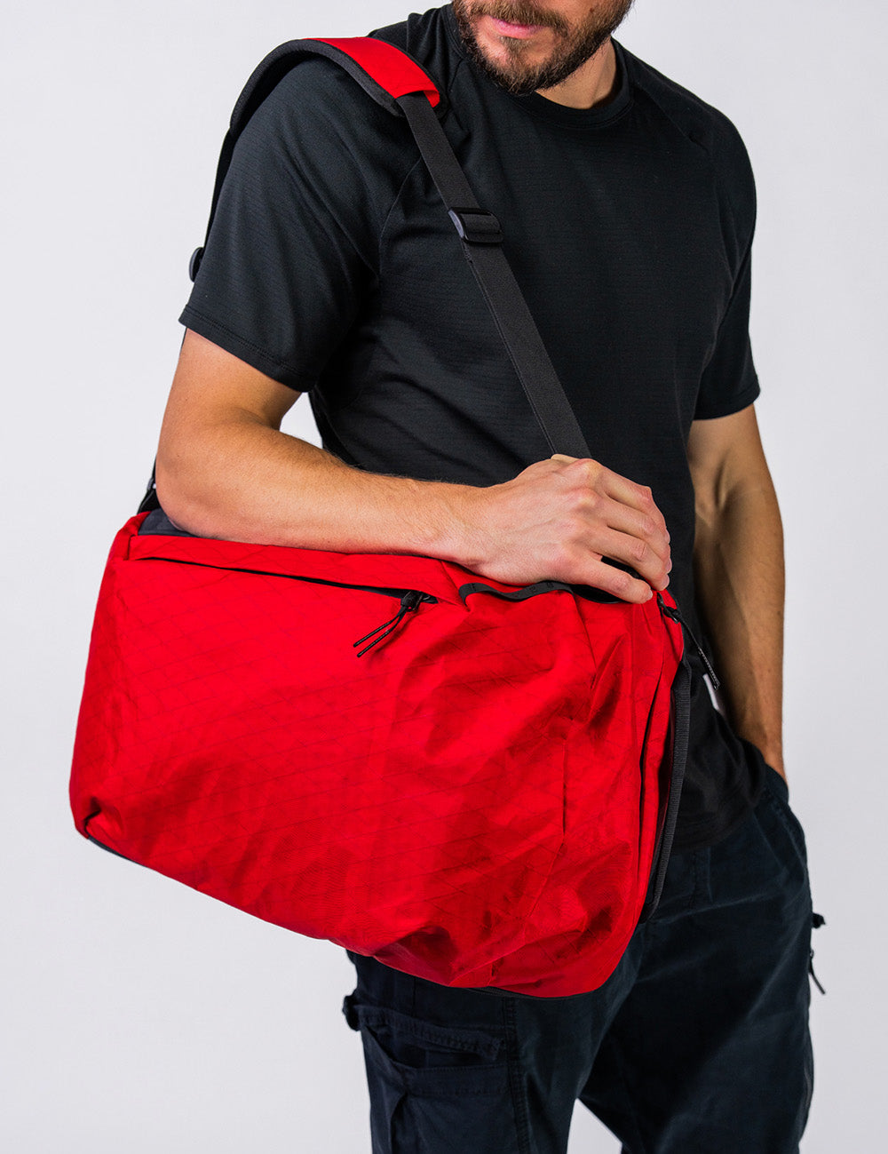 man holding red backpack like duffle on white background