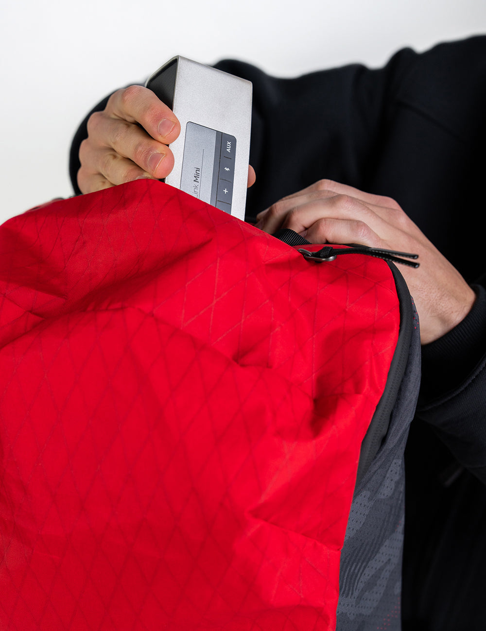 placing speaker into red backpack 