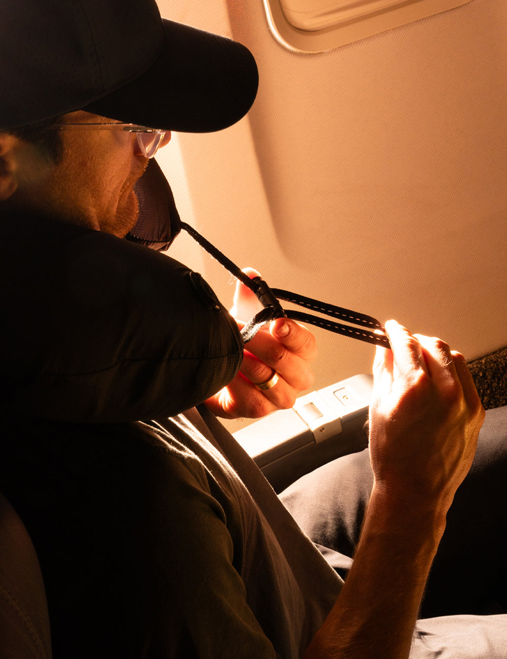 man on airplane, cinching neck pillow closed