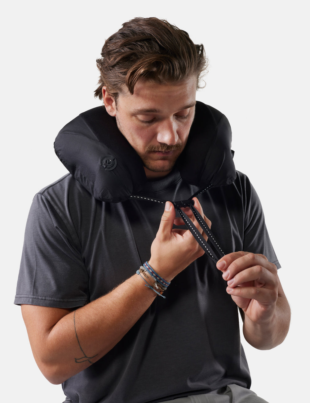 Man wearing a black neck pillow against a white background