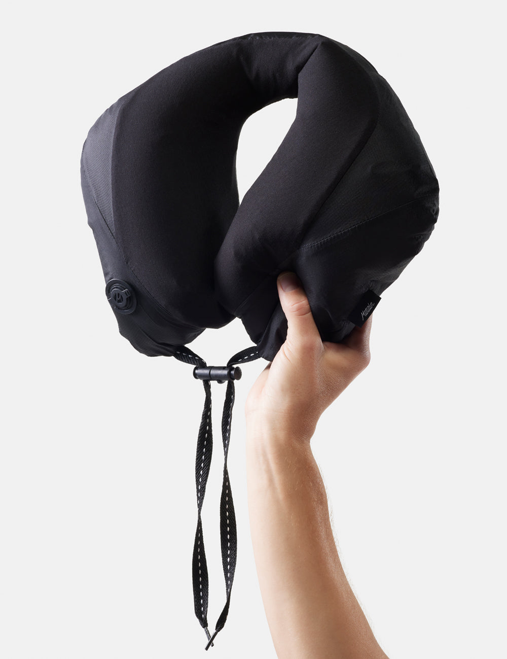 Black travel neck pillow held by a hand against a white background