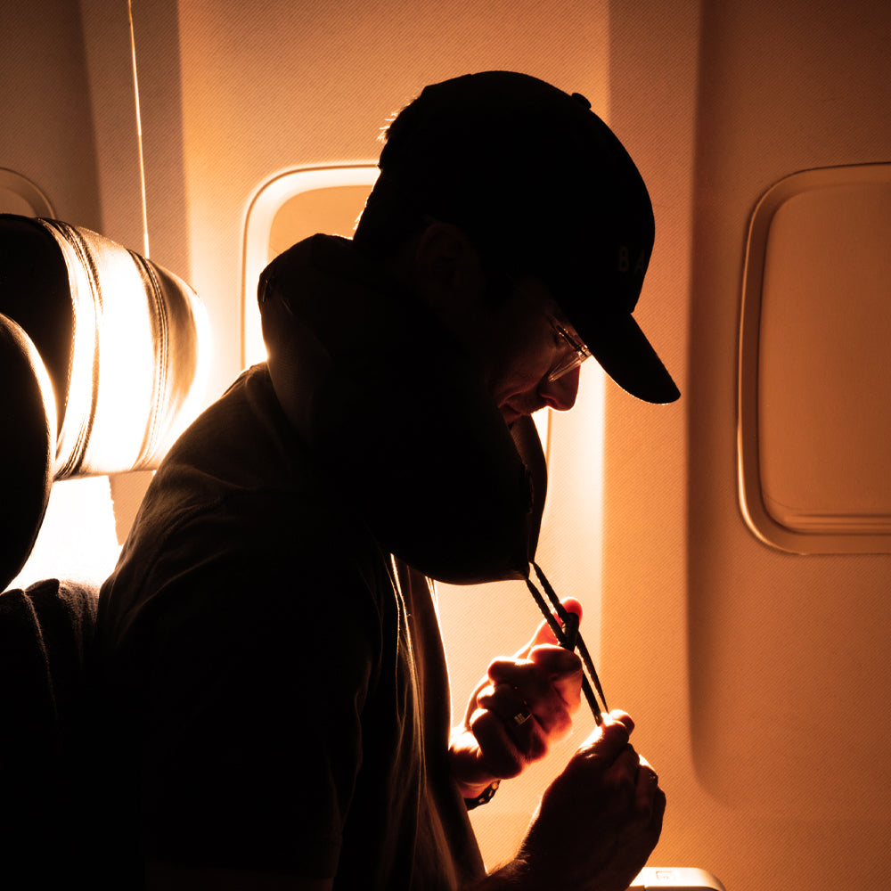 Man on airplane, cinching down travel pillow