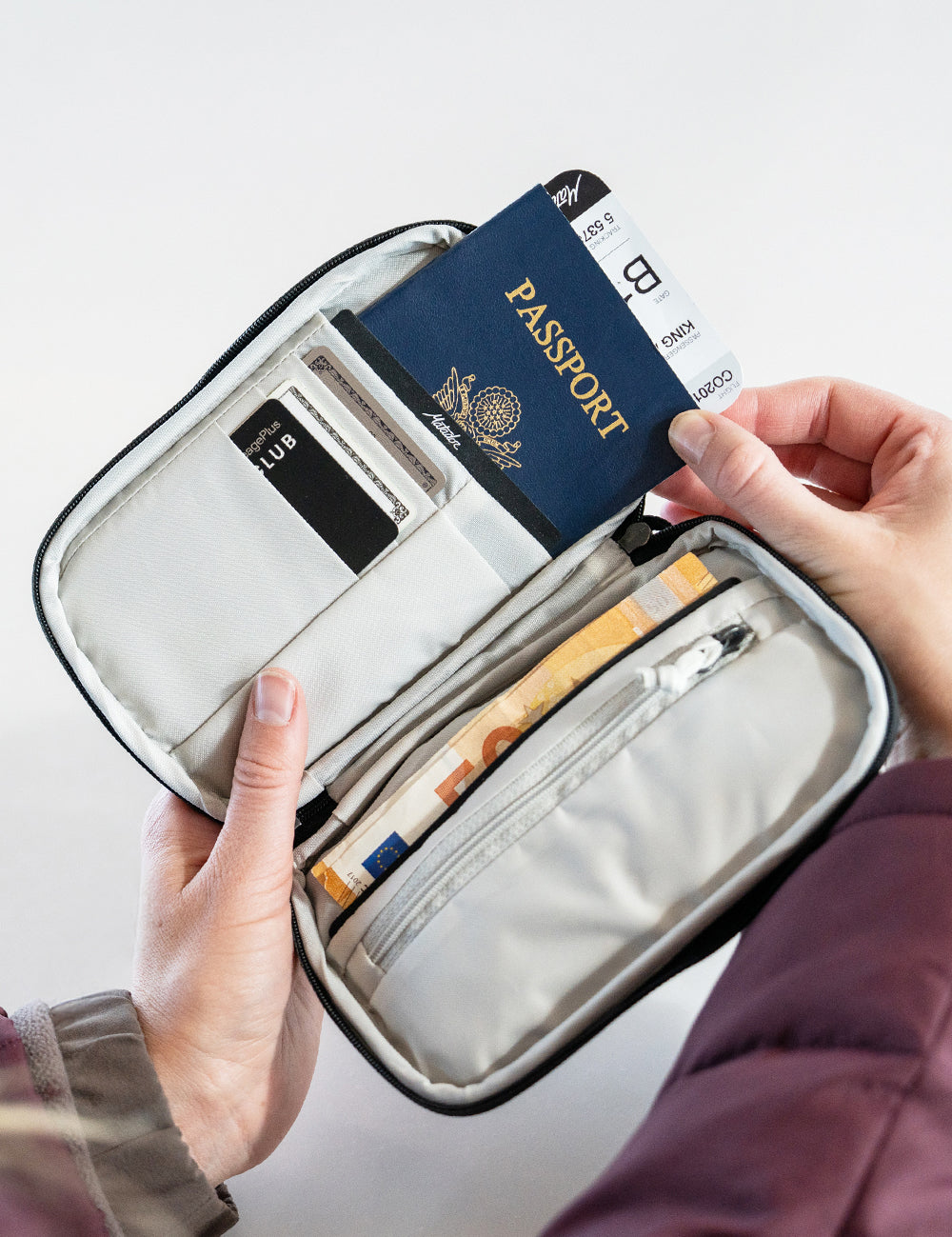 hands pulling passport and ticket out of travel wallet
