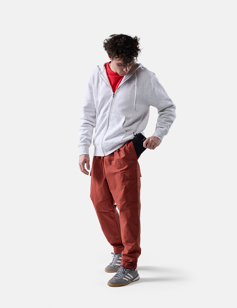 man on white background placing travel wallet in his pant pocket