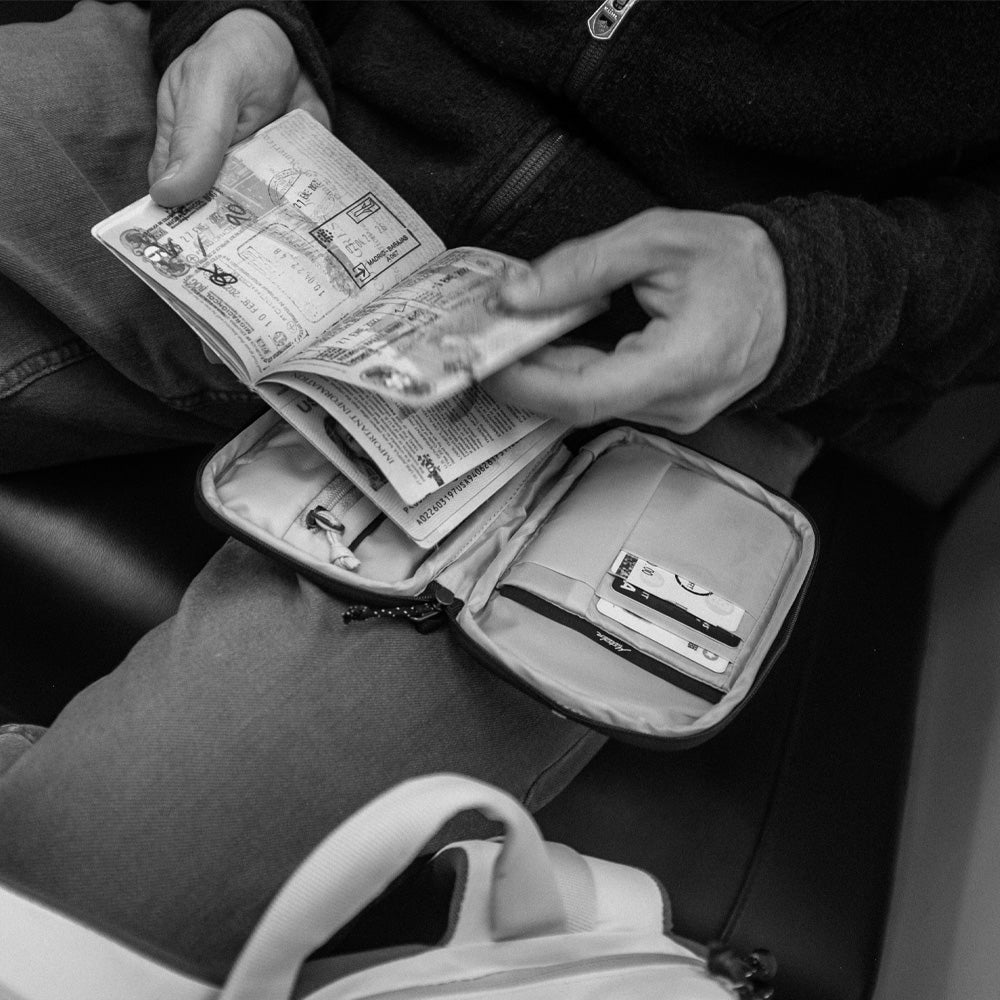 man flipping through passport stamps with full travel wallet