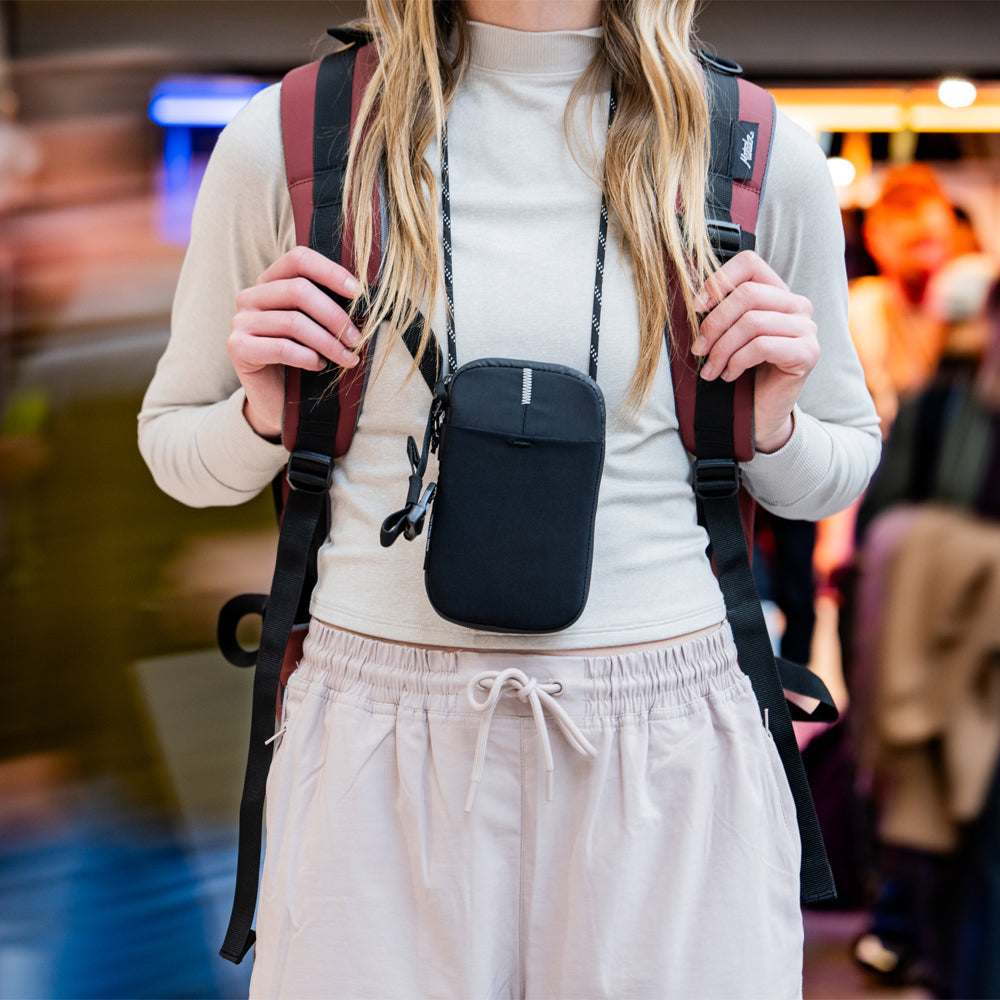 woman wearing travel wallet in front of busy colorful motion