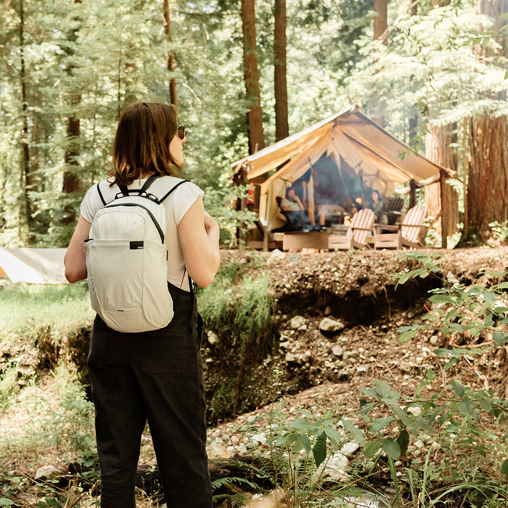 Woman in forest wearing white backpack
