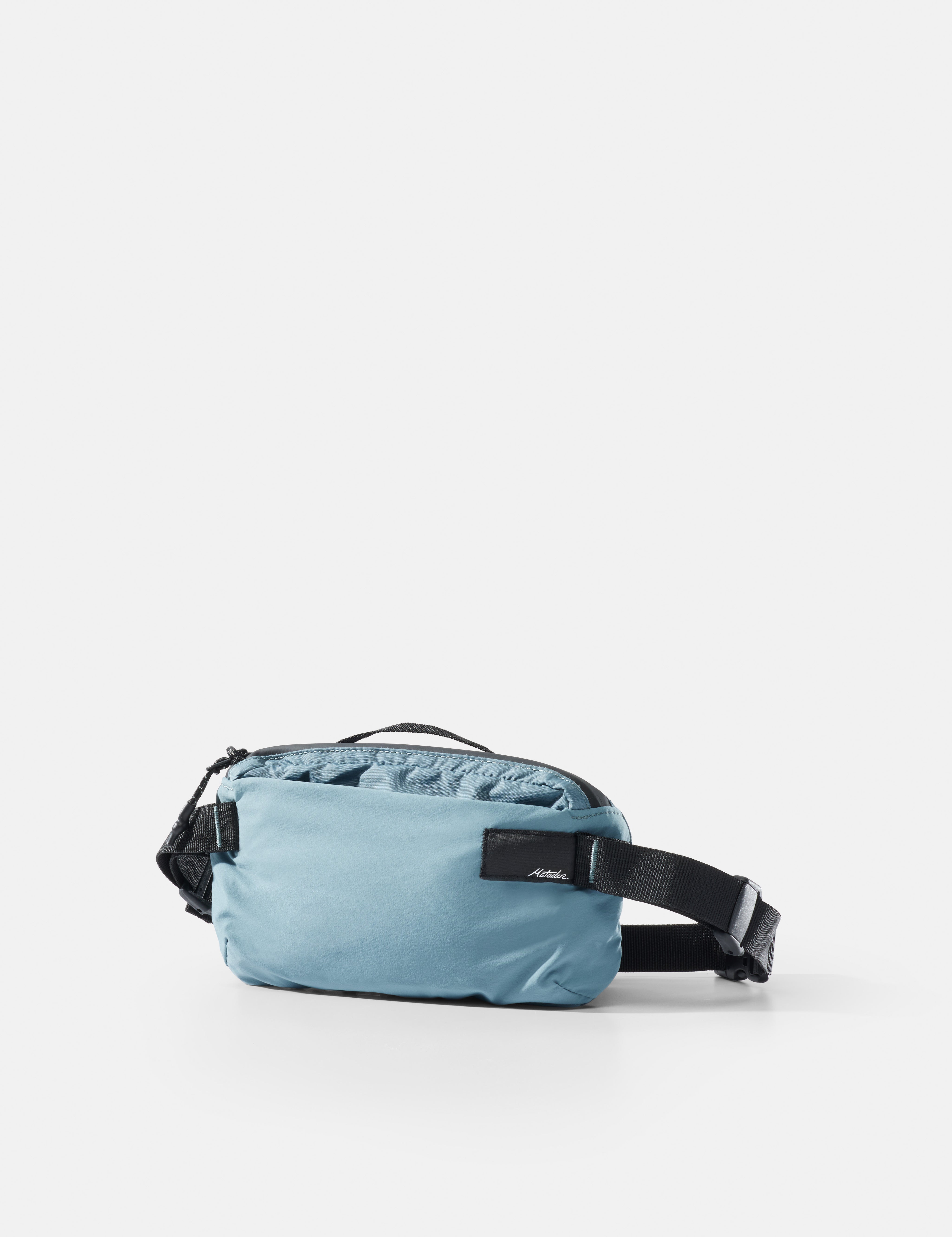 Light blue waist bag with black strap on a white background