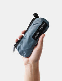 Hand holding a blue pouch with a brand label on a light background