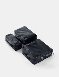 Three black packing cubes stacked on a white background
