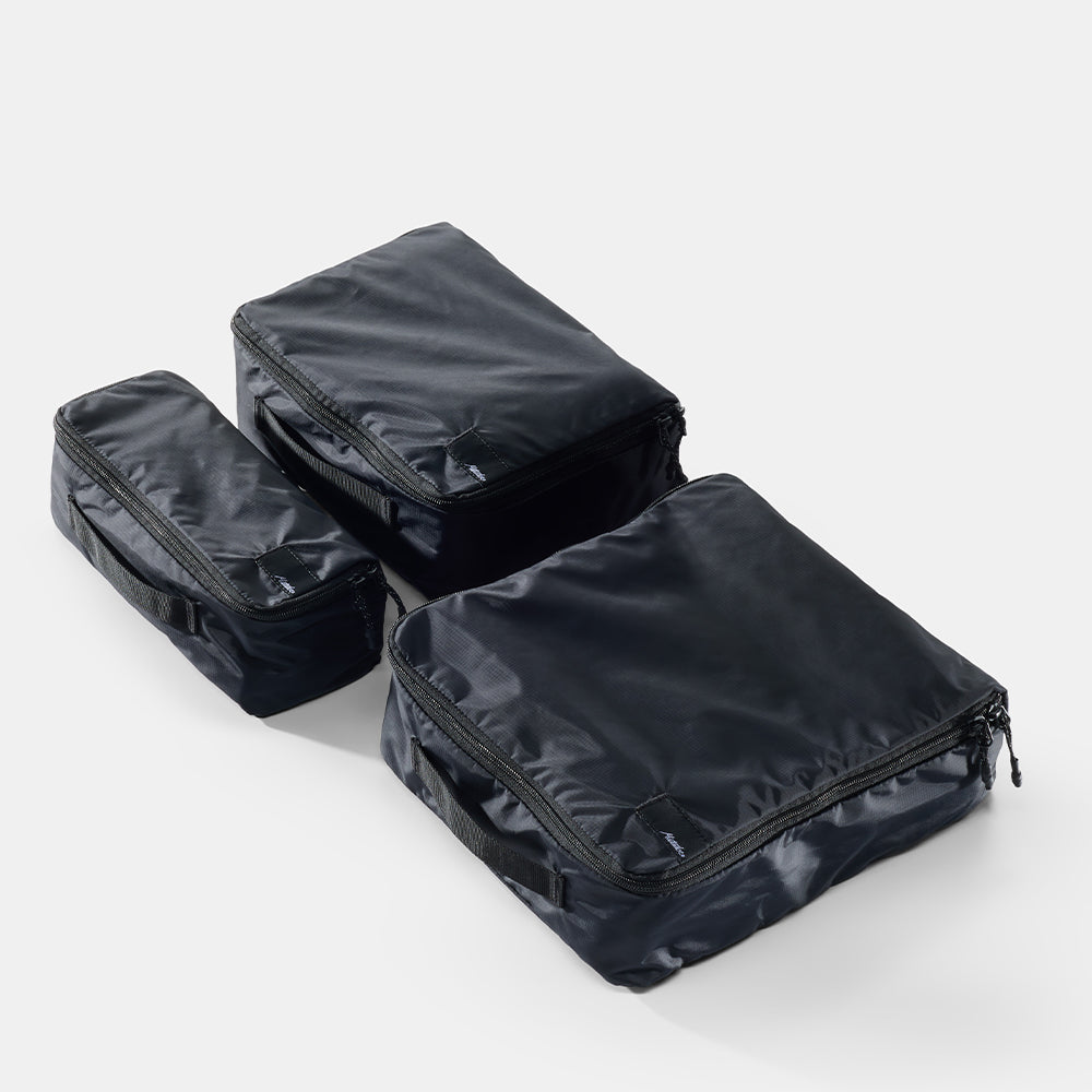 Three black packing cubes stacked on a white background