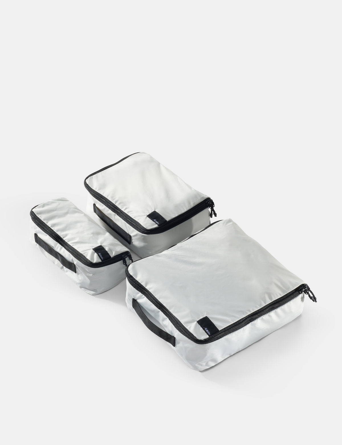 Set of white packing cubes with black zippers on a white background