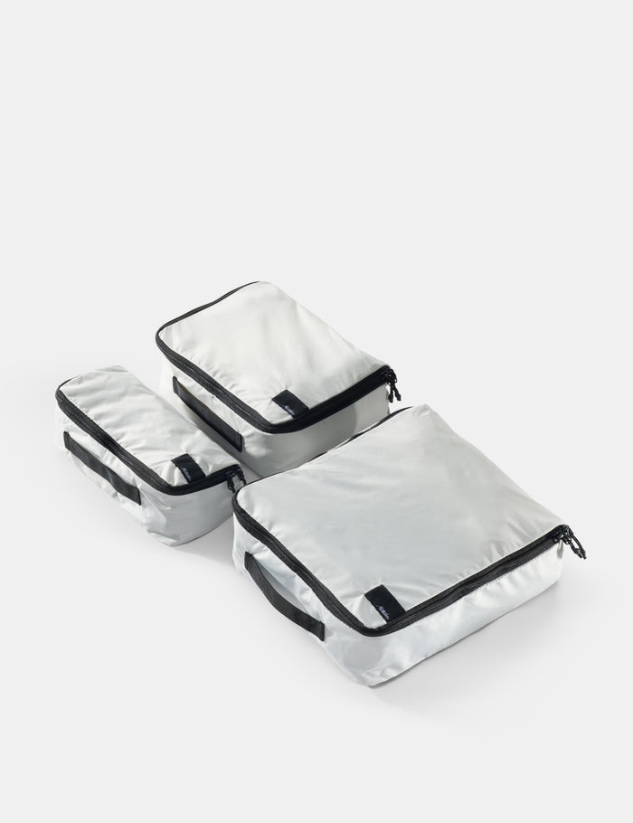Set of white packing cubes with black zippers on a white background