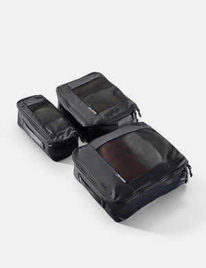 Set of black travel packing cubes on a light gray background