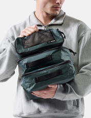 Person holding a green travel packing cube set against a neutral background