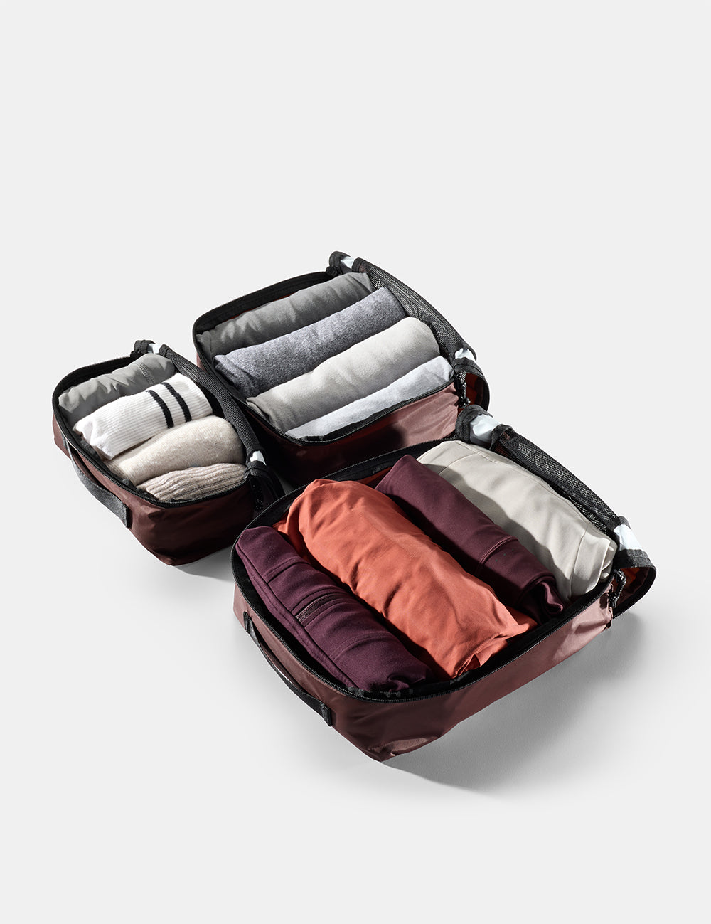 Compact travel packing cube with clothes on a light gray background