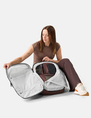 Woman unpacking garnet packing cubes on a white background