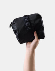 Black compression bag held by a hand on a light gray background