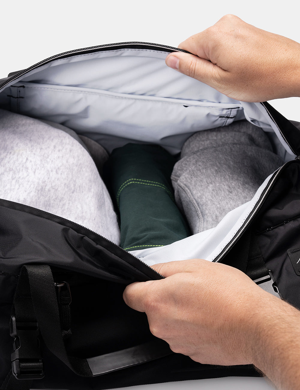 Hands holding duffel bag open to reveal light colored interior fabric
