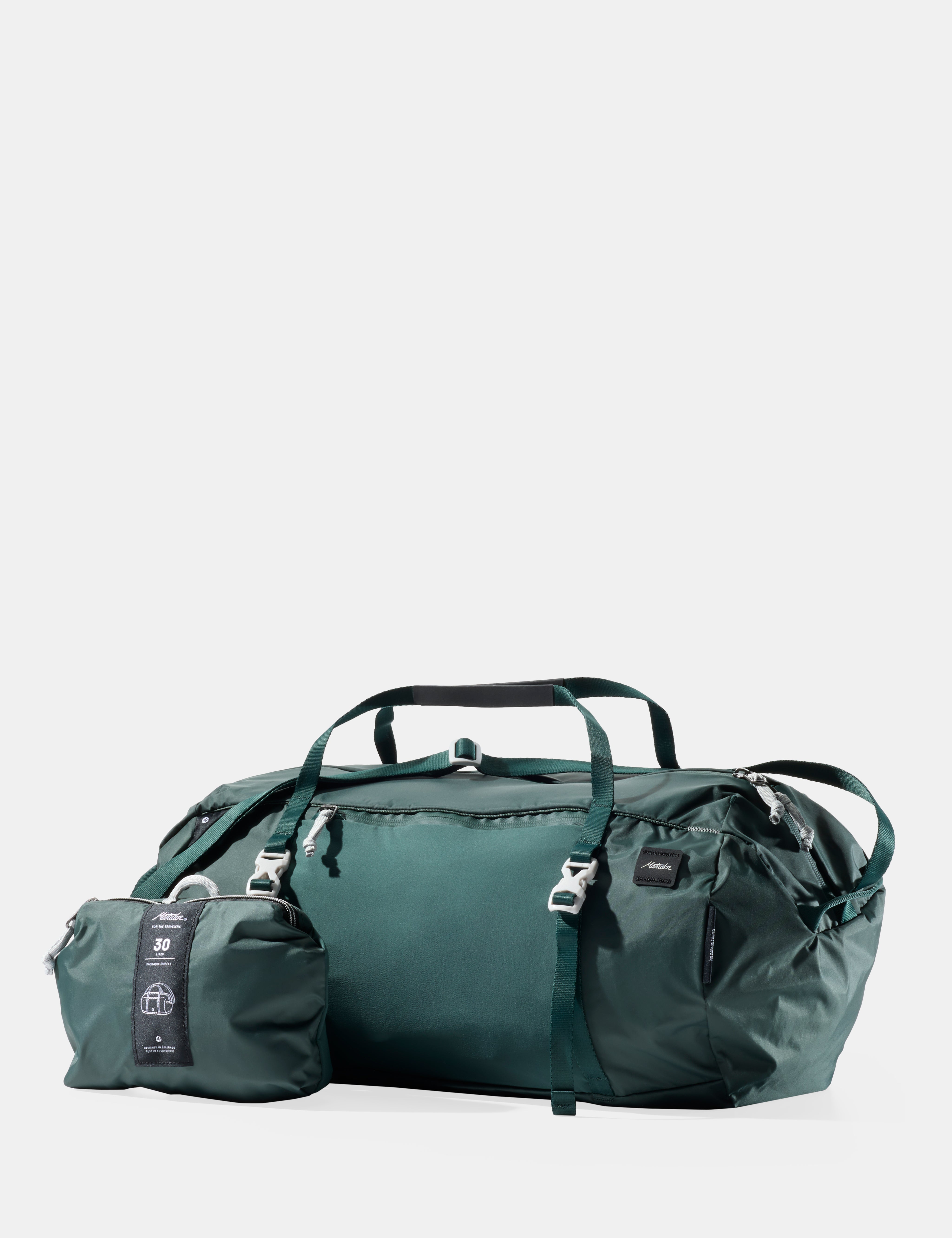 Green travel bag with smaller pouch on a light gray background