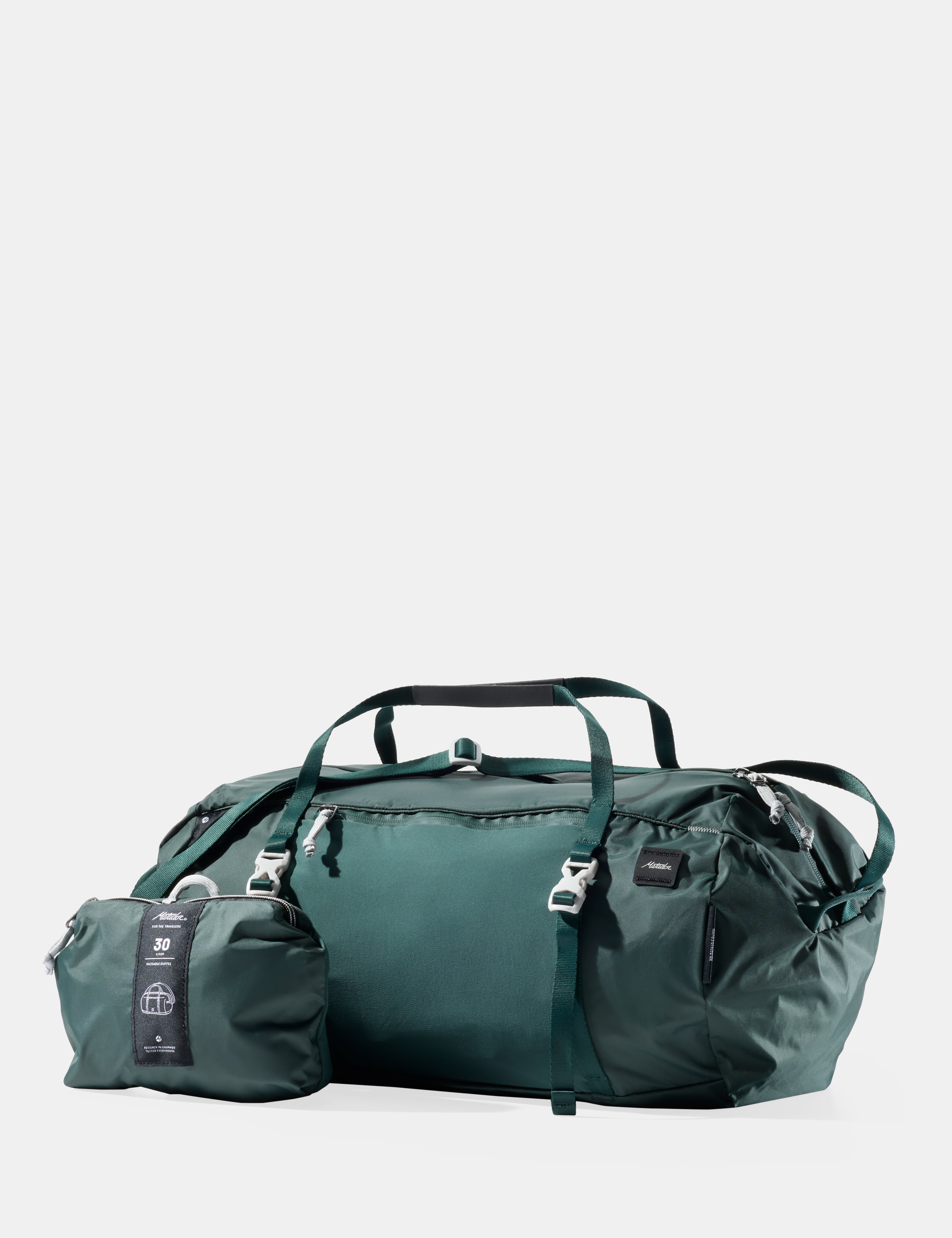 Green travel bag with smaller pouch on a light gray background