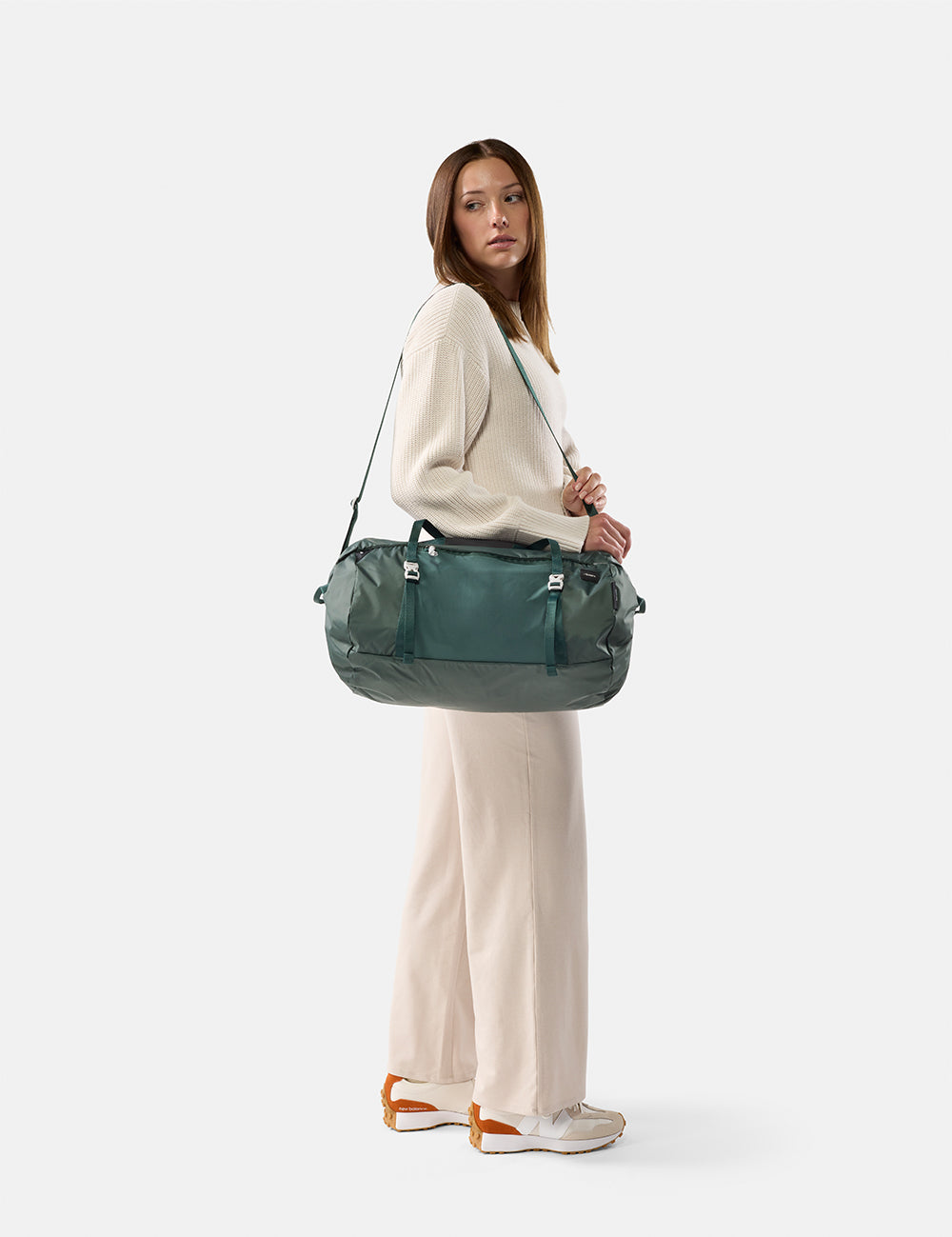 Woman holding a green duffel bag against a white background