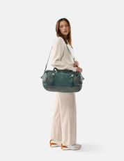 Woman holding a green duffel bag against a white background