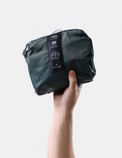 Hand holding a juniper compression bag with a visible brand label on a light gray background