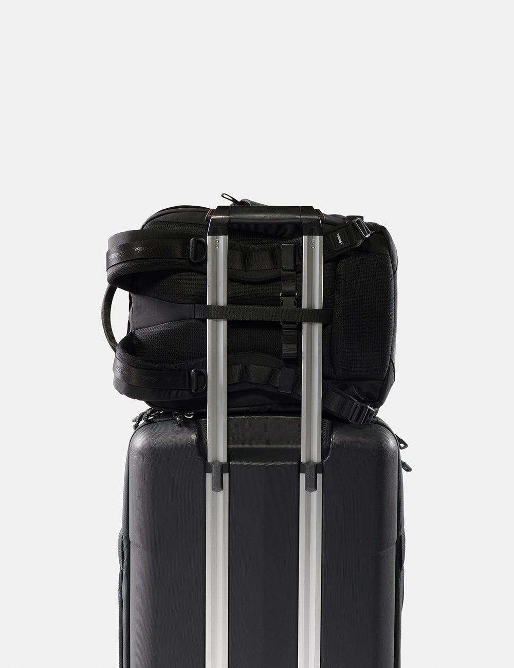 Black backpack and suitcase stacked on a white background