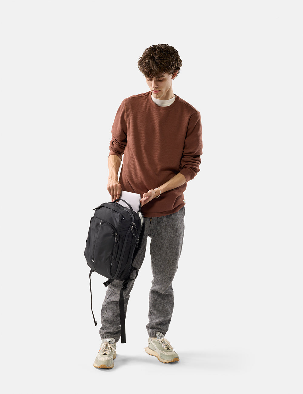 Man holding a black backpack on a white background