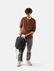 Man holding a black backpack on a white background