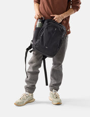 Person wearing a black backpack with a plain background