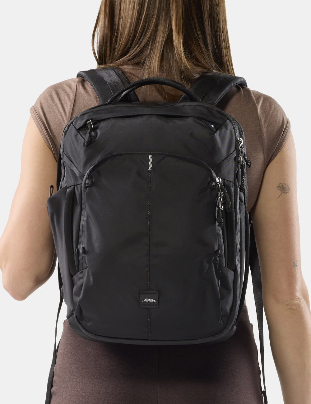 woman in brown wearing a black backpack