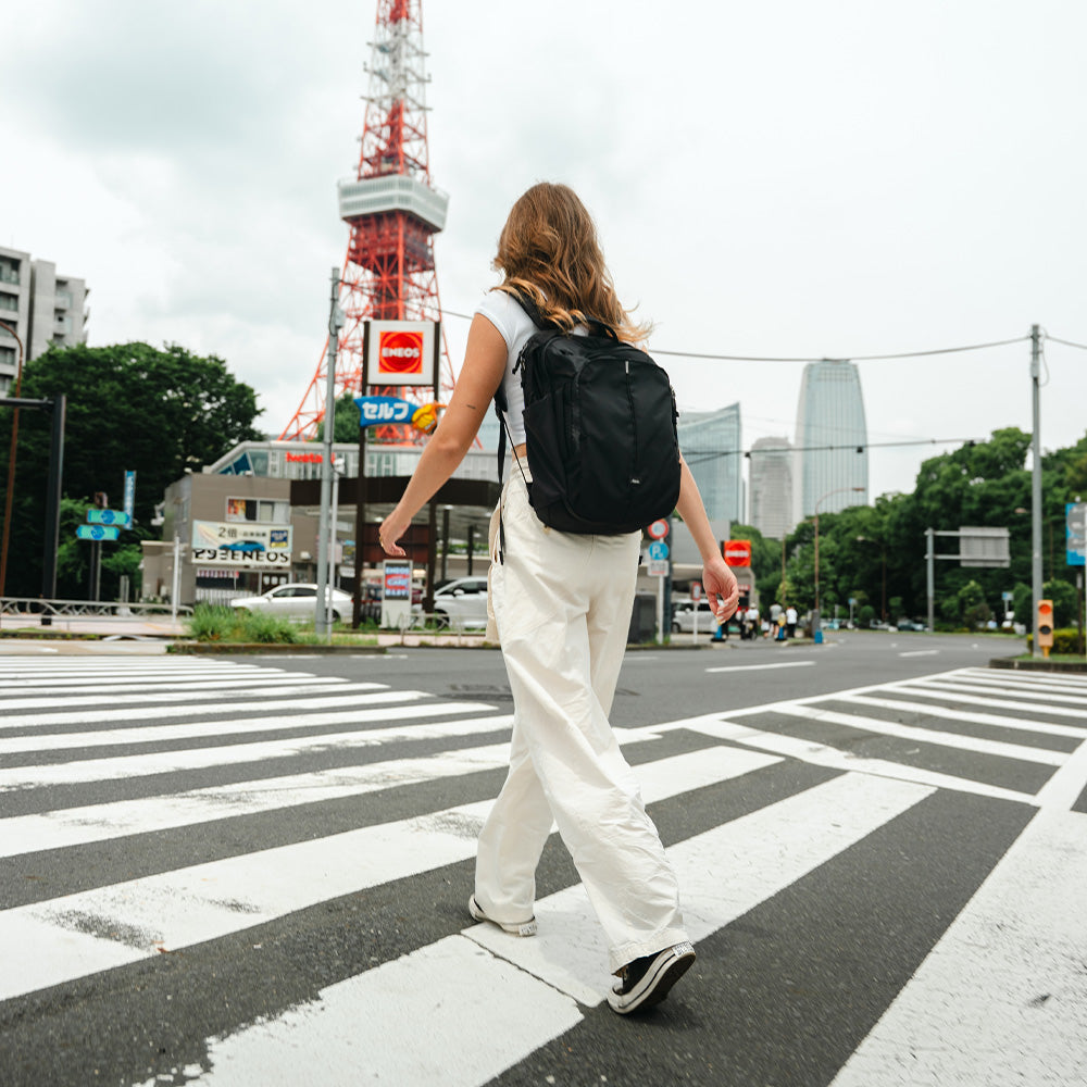 person crossing japanese street with black backpack